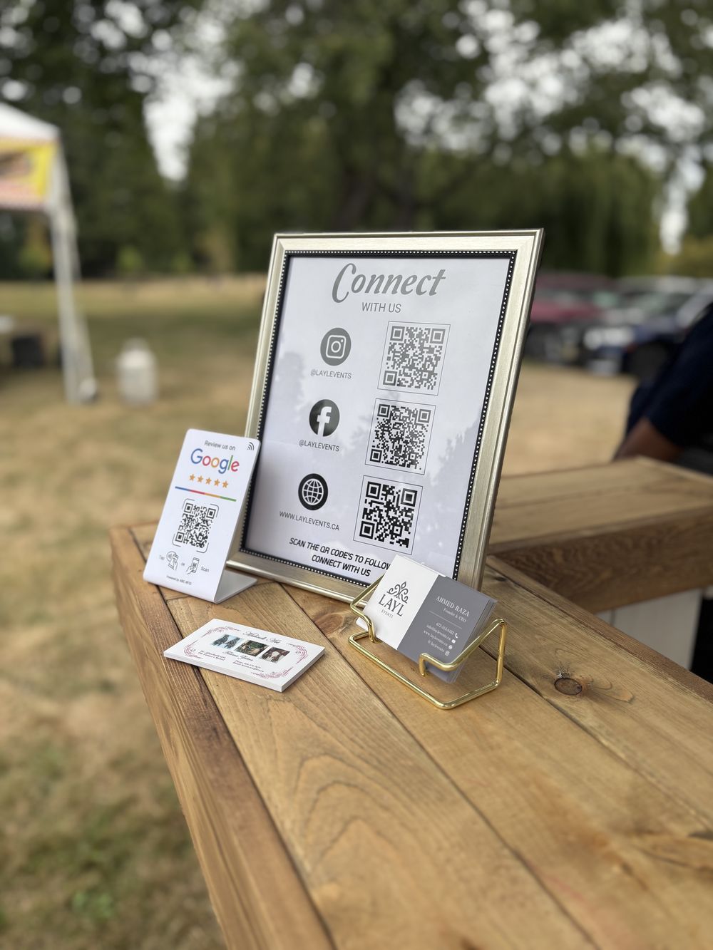 Layl welcome table with a framed sign and business cards at an outdoor event
